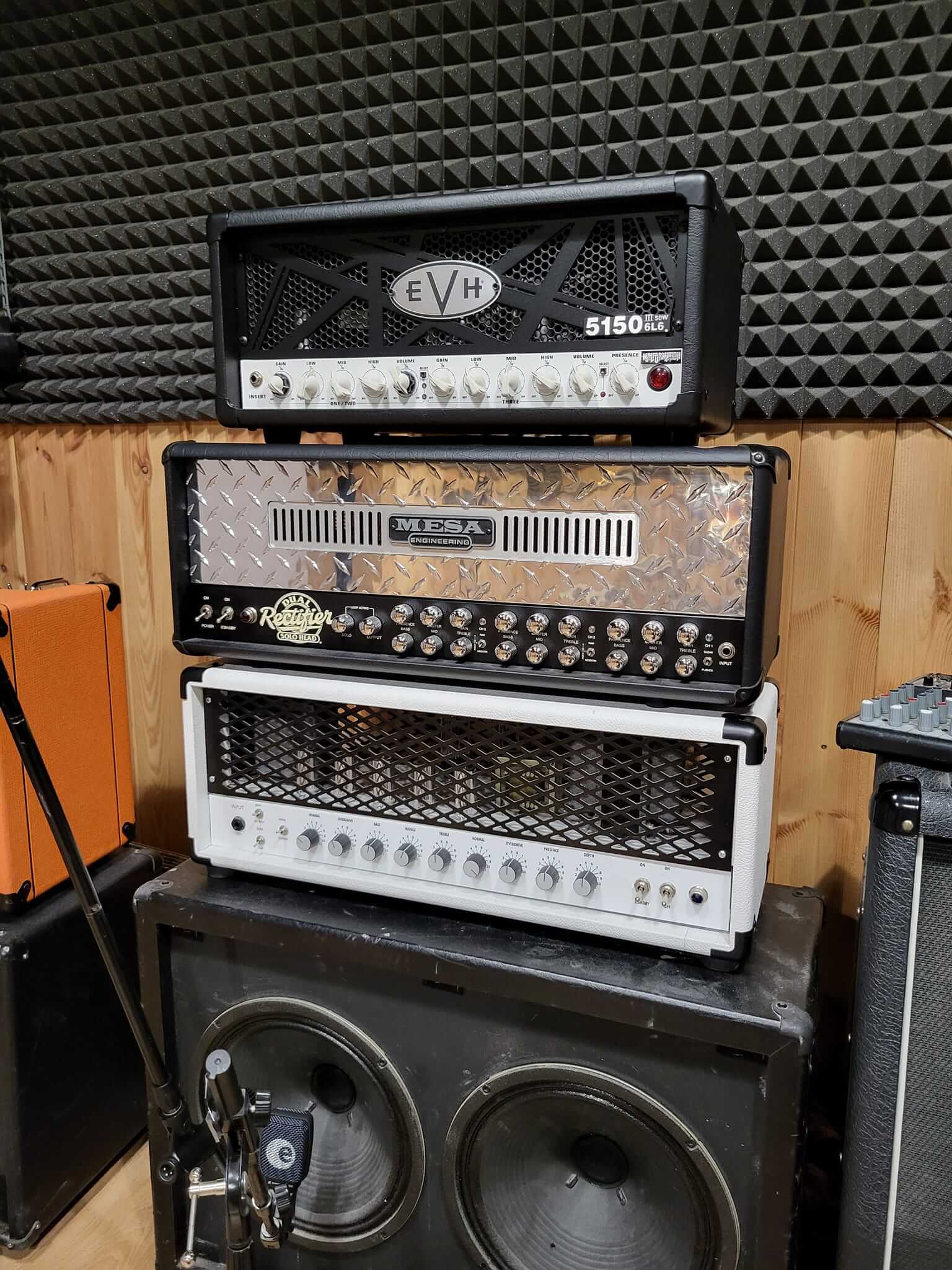 Stack of guitar amplifiers including EVH 5150, Mesa Boogie, and a white amp head, ideal for professional music studios.